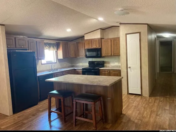a kitchen with stainless steel appliances a refrigerator a sink a stove a microwave a center island and wooden floor
