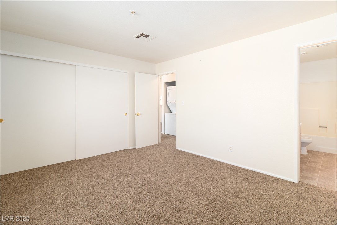 2028 Mesquite Lane, Unit 302 Laughlin, NV 89029 - Photo 19 of 60 Primary bedroom featuring light carpet, a closet, and ensuite bath