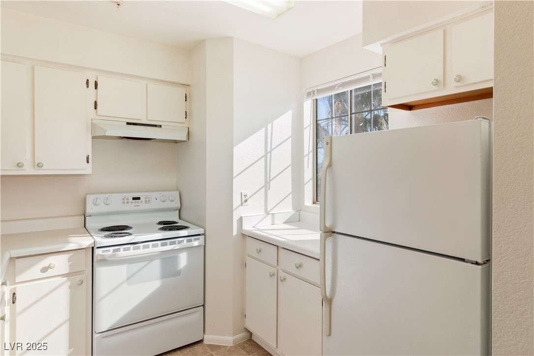 2028 Mesquite Lane, Unit 302 Laughlin, NV 89029 - Photo 6 of 60 Kitchen with white appliances, under cabinet range hood, light countertops, and light tile patterned floors
