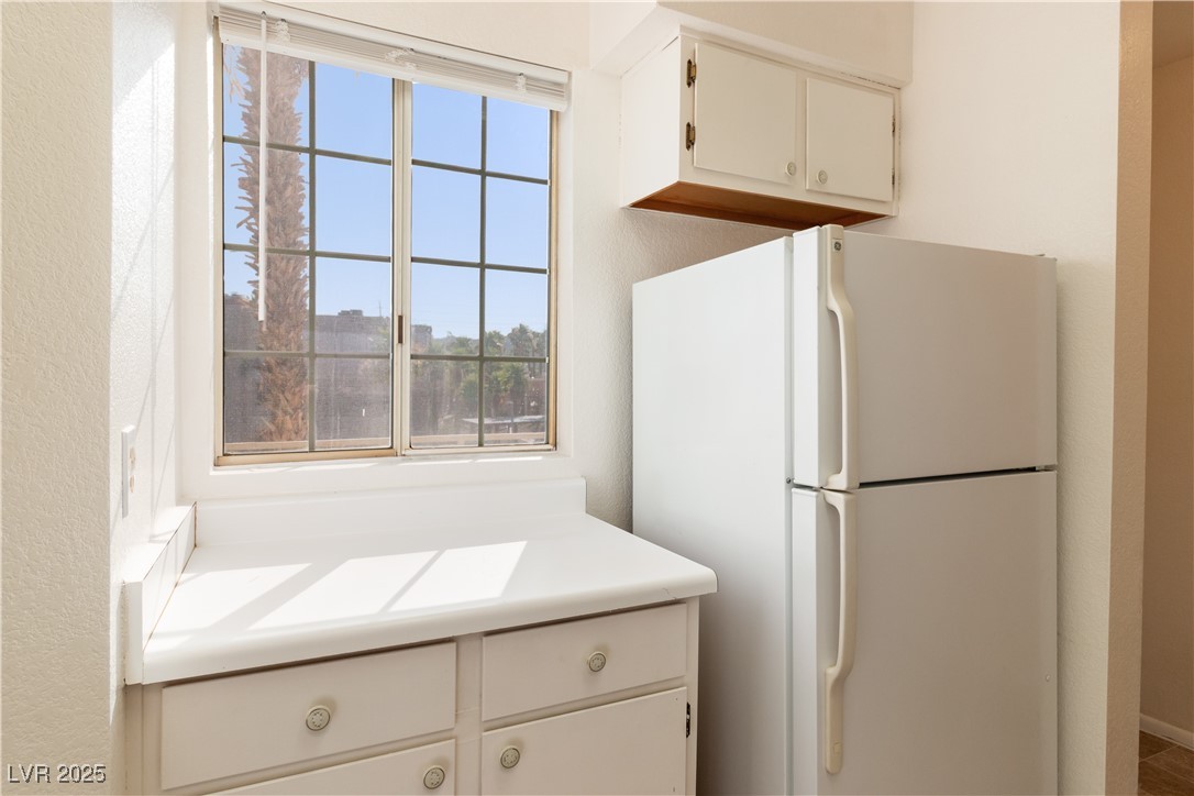 2028 Mesquite Lane, Unit 302 Laughlin, NV 89029 - Photo 8 of 60 Kitchen with freestanding refrigerator, plenty of natural light, light countertops, white cabinets, and a textured wall