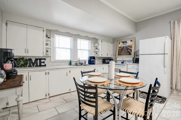 a kitchen with a dining table chairs and white appliances