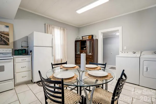 a kitchen with a dining table chairs and refrigerator