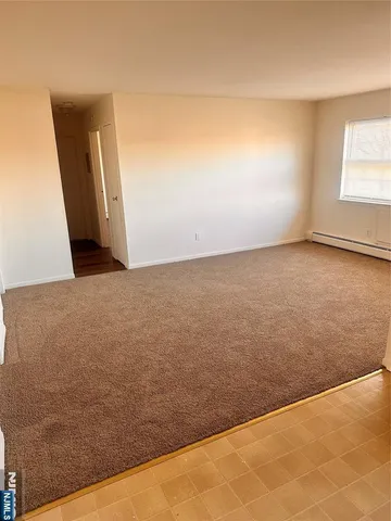 an empty room with wooden floor closet and windows