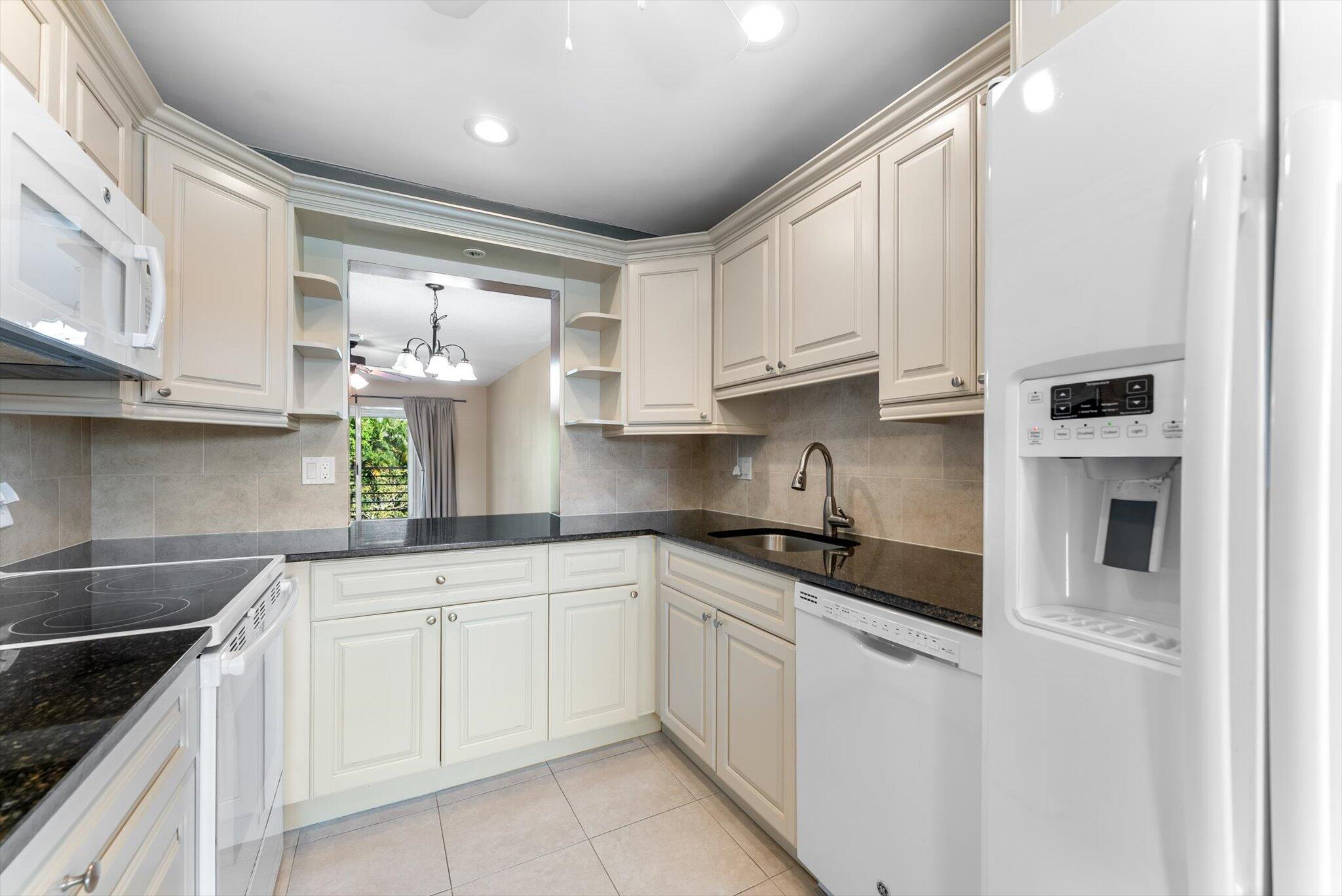 5321 Poppy Place, Unit 203 Delray Beach, FL 33484 - Photo 11 of 31 a kitchen with white cabinets and appliances