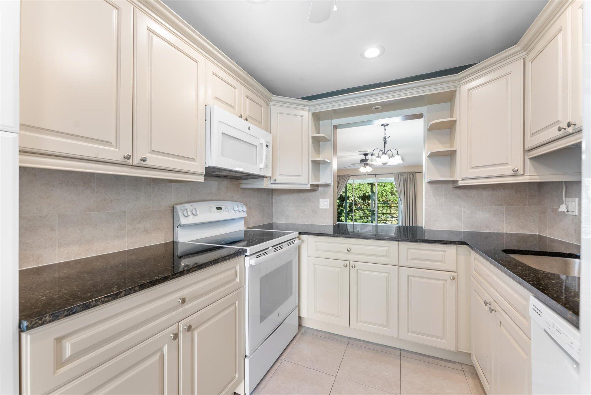 5321 Poppy Place, Unit 203 Delray Beach, FL 33484 - Photo 10 of 31 a kitchen with white cabinets and white appliances