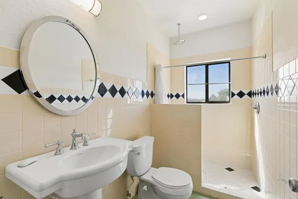 a bathroom with a sink a mirror a toilet and shower