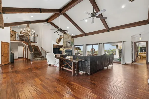 a view of a livingroom with furniture wooden floor stairs and windows