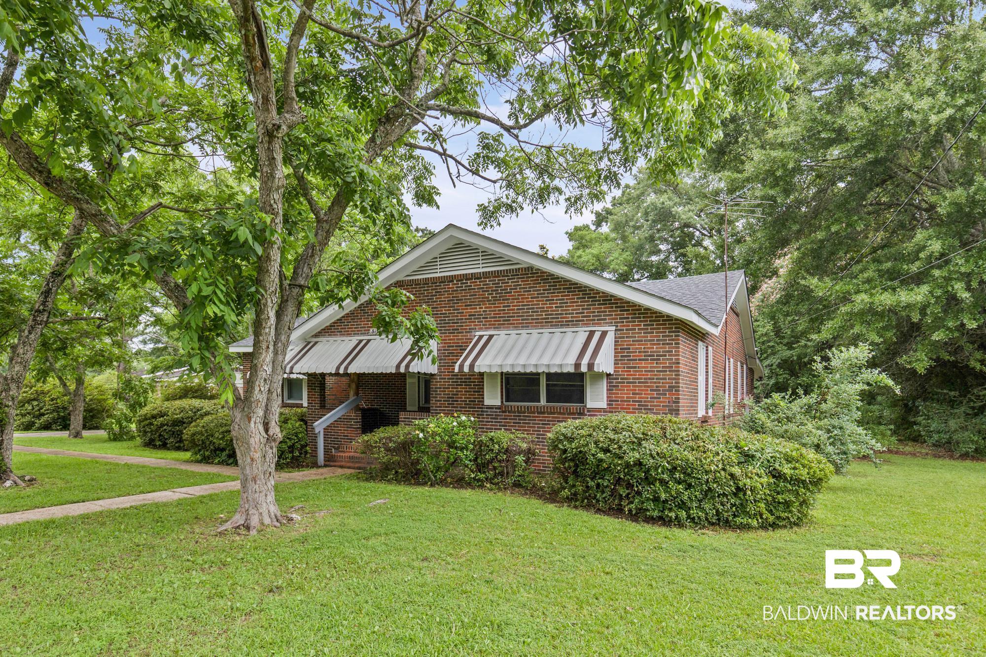 312 Sutherland Drive Mobile, AL 36611 - Photo 2 of 28 Brick exterior residence featuring a gabled roofline and striped awnings over the windows