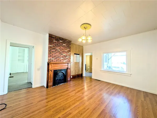 a view of empty room with fireplace and wooden floor
