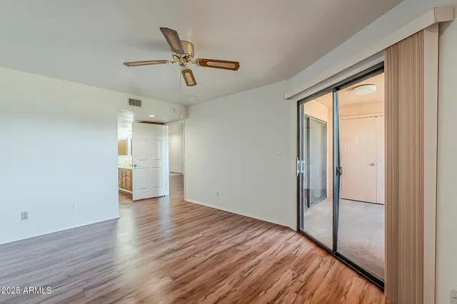 a view of empty room with wooden floor and fan