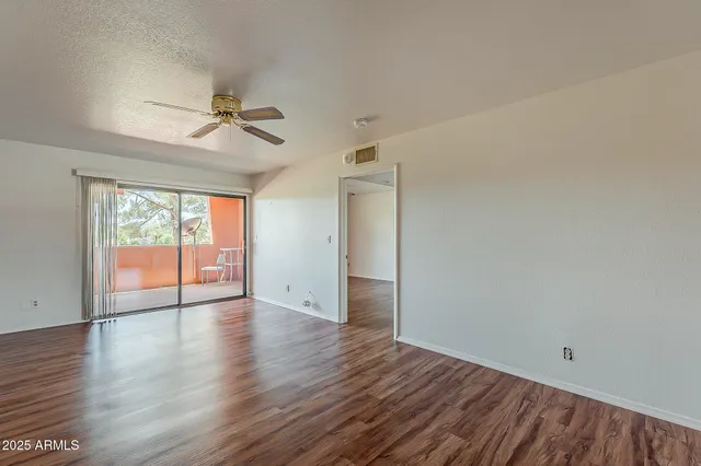 a view of empty room with wooden floor and fan