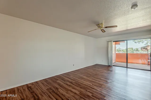 a view of an empty room with a window and wooden floor