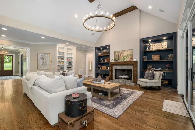 a living room with furniture a fireplace and a chandelier