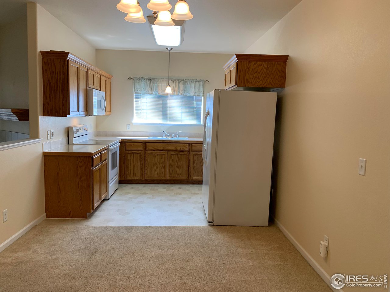 124 Beacon Way, Unit B Windsor, CO 80550 - Photo 3 of 26 a kitchen with granite countertop a refrigerator and a sink