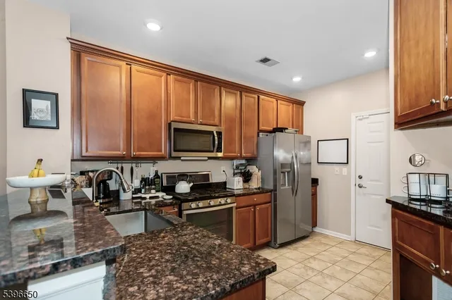a kitchen with stainless steel appliances granite countertop a refrigerator stove top oven a sink and dishwasher