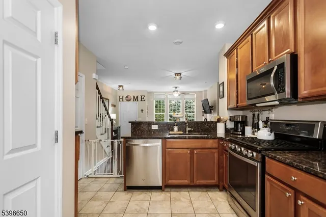 a kitchen with stainless steel appliances granite countertop a sink a stove a refrigerator cabinets and a dining table