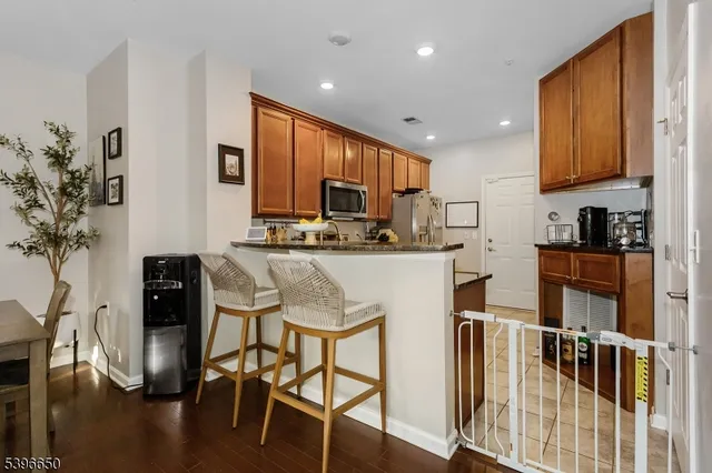 a kitchen with stainless steel appliances granite countertop a stove top oven a sink a dining table and chairs with wooden floor