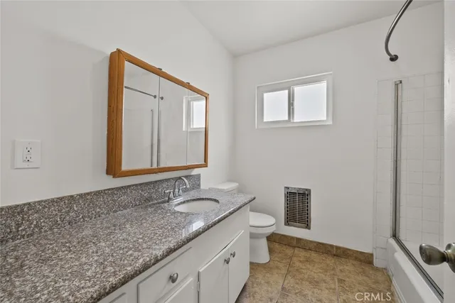 a bathroom with a granite countertop sink and mirror with bathtub