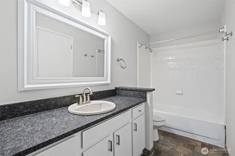 a bathroom with a granite countertop sink toilet and shower