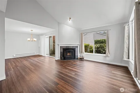 an empty room with wooden floor fireplace and windows