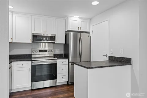 a kitchen with granite countertop white cabinets and stainless steel appliances