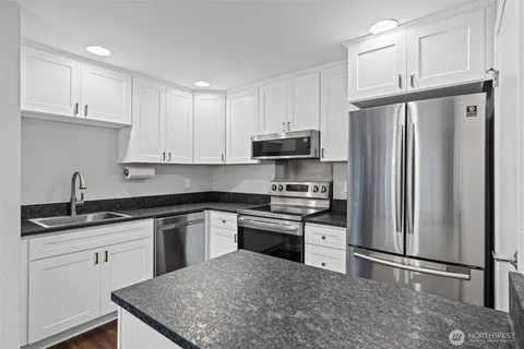 a kitchen with stainless steel appliances granite countertop a refrigerator sink and stove