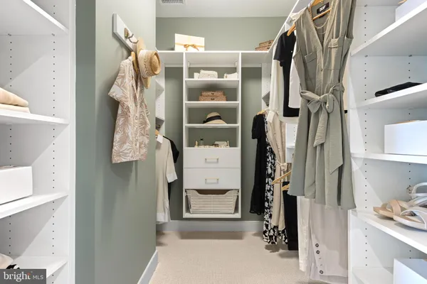 a view of walk in closet with clothes and shoes