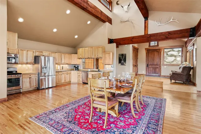 a living room with stainless steel appliances furniture wooden floor and a kitchen view