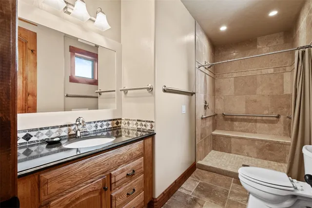 a bathroom with a sink a toilet a mirror and shower