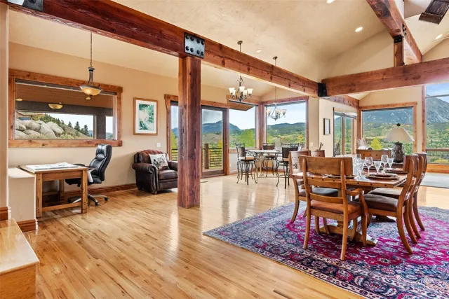 a dining room with wooden floor a large window and a rug