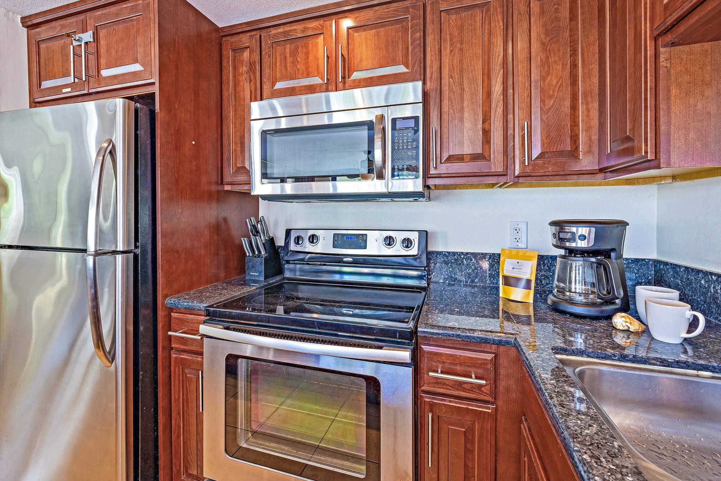 3543 Lower Honoapiilani Road, Unit H201 Lahaina, HI 96761 - Photo 12 of 31 a kitchen with stainless steel appliances granite countertop a stove microwave and refrigerator
