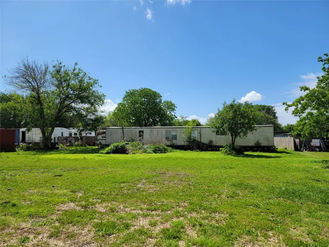 a backyard of a house with plants and large tree