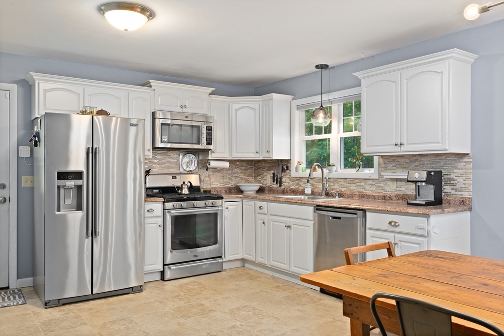 53 Mueller Road Holyoke, MA 01040 - Photo 17 of 40 a kitchen with stainless steel appliances granite countertop a stove a refrigerator a sink dishwasher a dining table and chairs with wooden floor