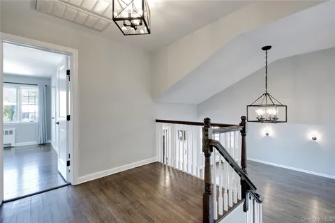 a view of empty room with wooden floor and stairs