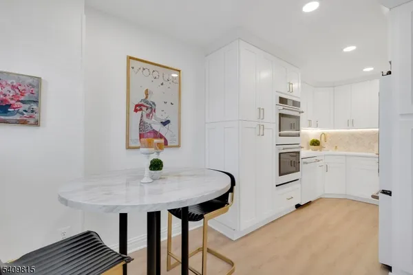 a kitchen with stainless steel appliances a stove a refrigerator and white cabinets with wooden floor