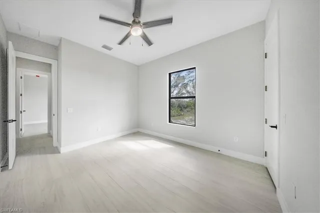 an empty room with windows and fan