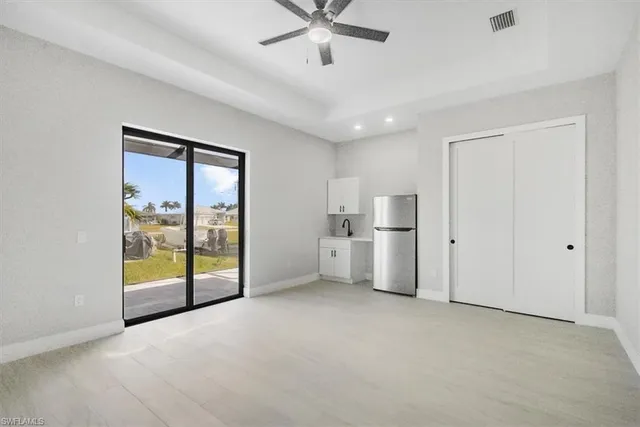 a view of an empty room with a window and a kitchen