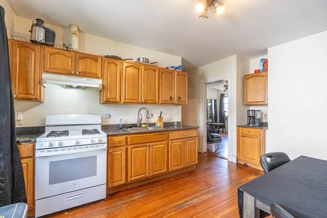 a kitchen with stainless steel appliances a stove a sink dishwasher and a refrigerator with wooden floor