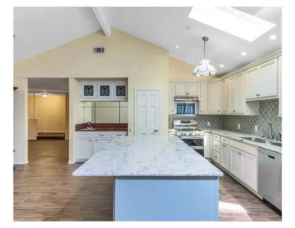 a kitchen with kitchen island a sink and a stove top oven with wooden floor