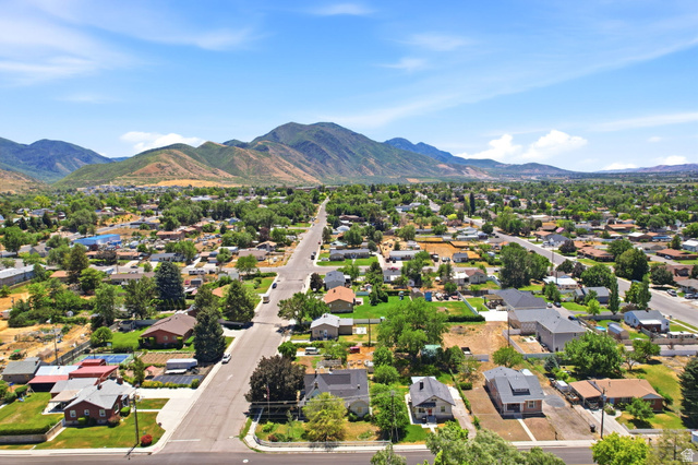 310 South 300 West Payson, UT 84651 - Photo 39 of 42 Expansive aerial perspective showcasing a residential area with varied housing styles and mature trees, set against a backdrop of distant mountains
