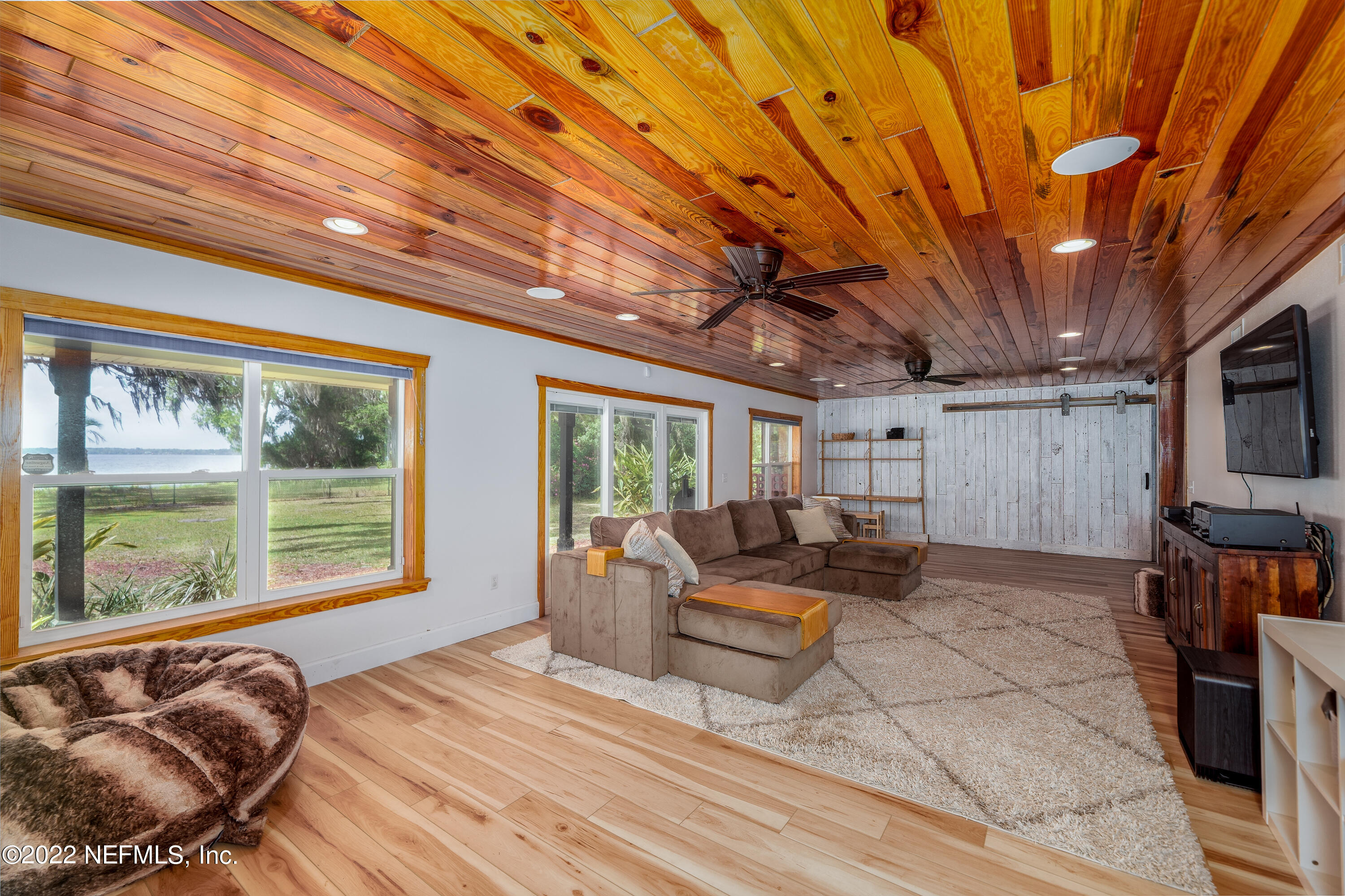 541 Federal Point Road East Palatka, FL 32131 - Photo 21 of 75 a living room with furniture a flat screen tv and floor to ceiling window