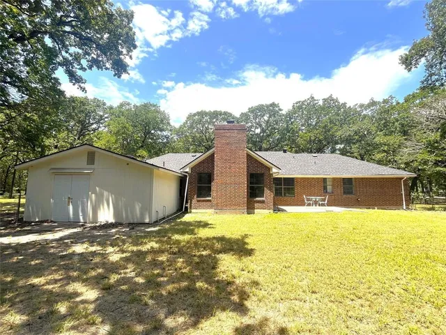 a front view of house with yard and trees in the background