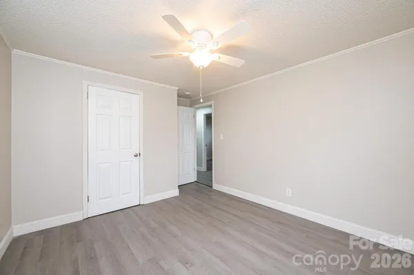 an empty room with wooden floor and fan