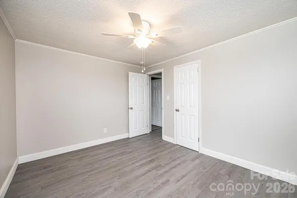 an empty room with wooden floor and fan