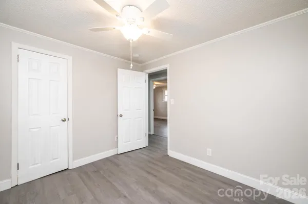 an empty room with a chandelier fan and closet area