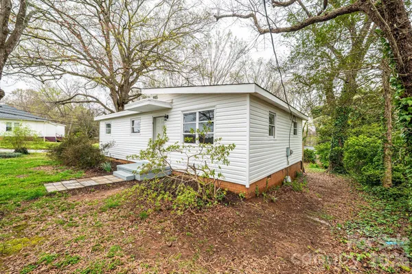 a white house that has a small yard and large trees
