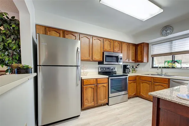 a kitchen with stainless steel appliances granite countertop a refrigerator a stove top oven a sink and dishwasher