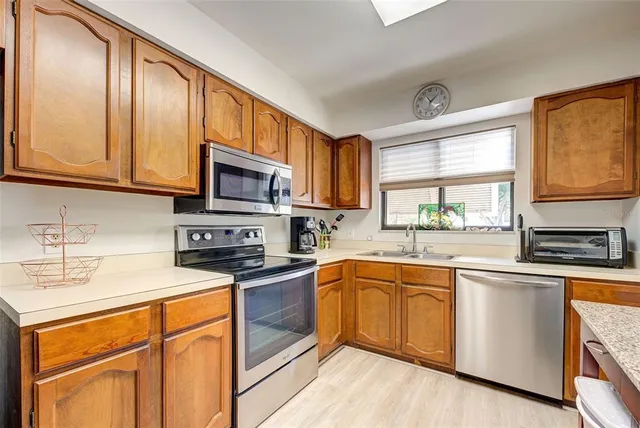 a kitchen with stainless steel appliances granite countertop a sink stove microwave and refrigerator