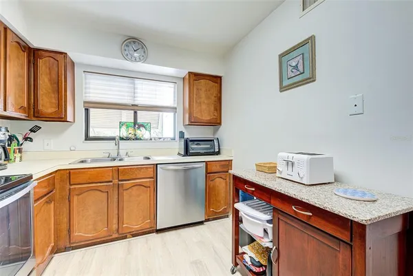 a kitchen with stainless steel appliances granite countertop a sink a stove cabinets counter space and a window