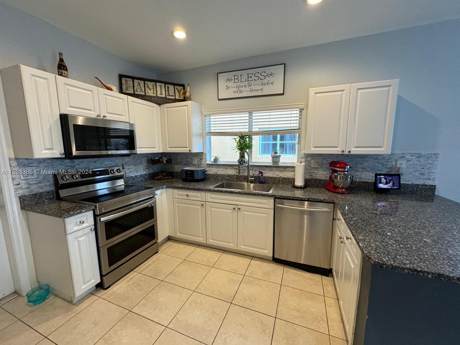 2841 Northeast 41st Place Homestead, FL 33033 - Photo 9 of 71 a kitchen with stainless steel appliances a stove a sink a microwave a counter top space and cabinets